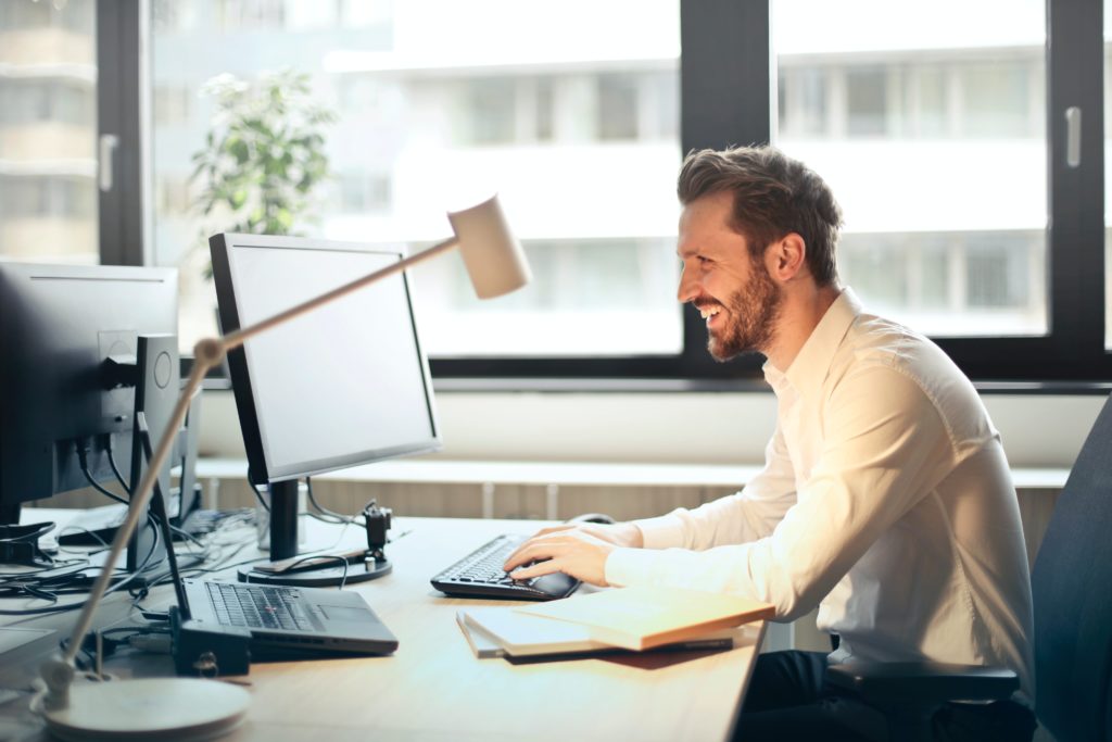 A picture of a man looking at his screen with joy because this article is about data lakehouses which offer the best of both data warehouses and data lakes which address managing structured and unstructured data to produce business insights and analytics.